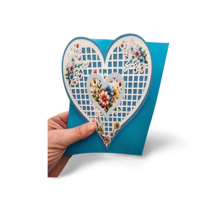 Heart-shaped card with floral design held by a hand on a white background