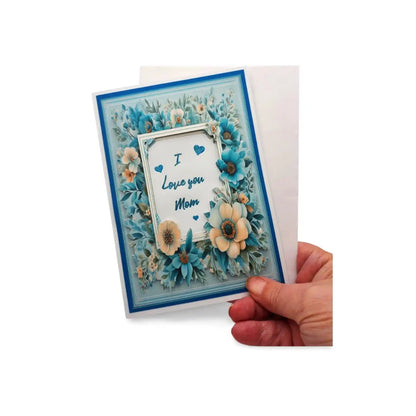 Greeting card with floral design and 'I love you Mom' text held by a hand on a white background