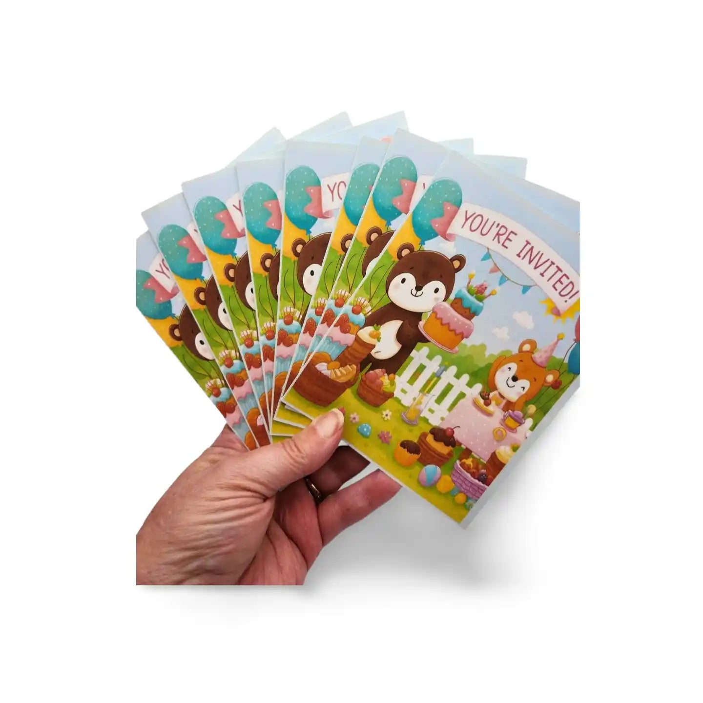 Hand holding a stack of colorful children's invitations with cartoon animals on a white background