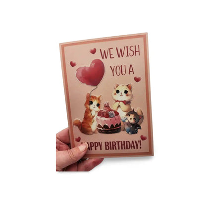 Birthday card with cartoon cats and a cake, held by a hand on a white background