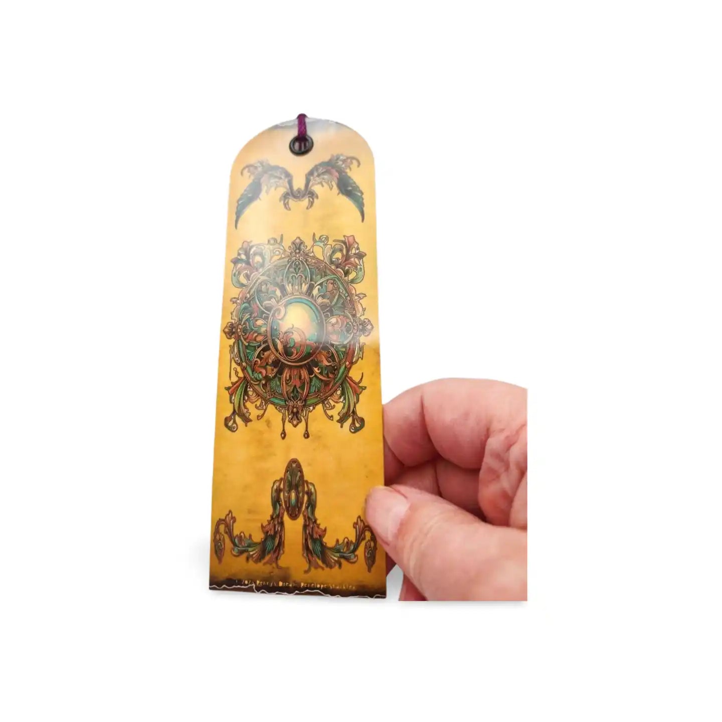 Decorative bookmark with intricate designs held by a hand on a white background