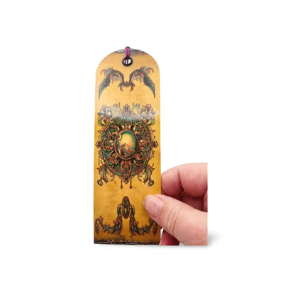 Decorative bookmark with intricate designs held by a hand on a white background