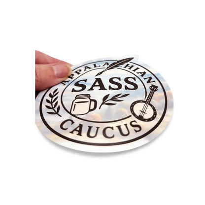 Sticker with 'Appalachian Sass Caucus' design held by a hand on a white background