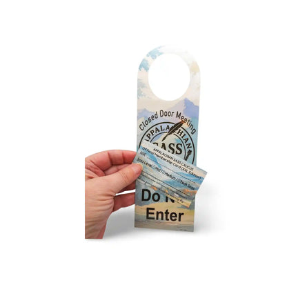Hand holding a door hanger with text and graphics on a white background