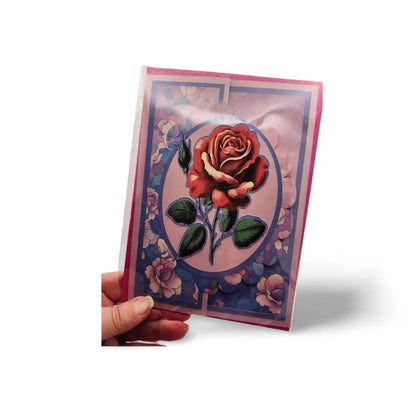Greeting card with a red rose design held by a hand on a white background