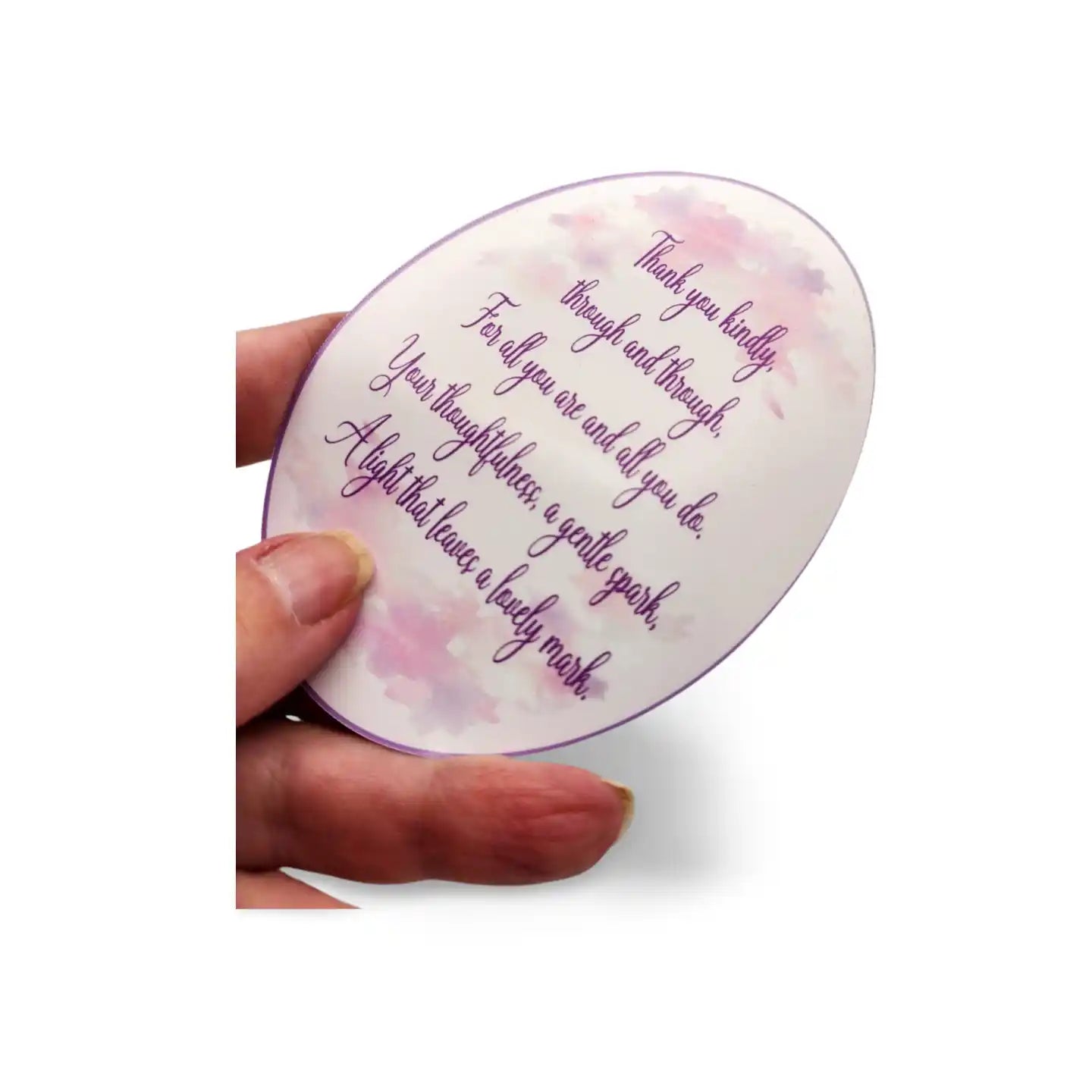 Round decorative item with text and floral design held by a hand on a white background