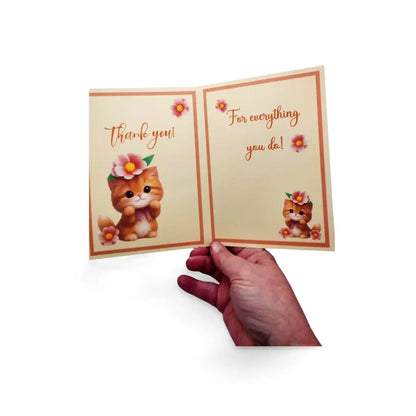 Open card with cartoon cat holding flowers and text 'Thank you! For everything you do!' held by a hand on a white background.