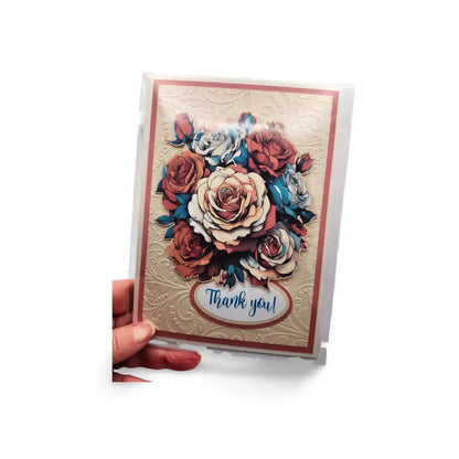 Greeting card with floral design and 'Thank you!' text held by a hand on a white background
