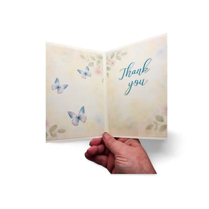 Hand holding a card with butterflies and 'Thank you' text on a white background