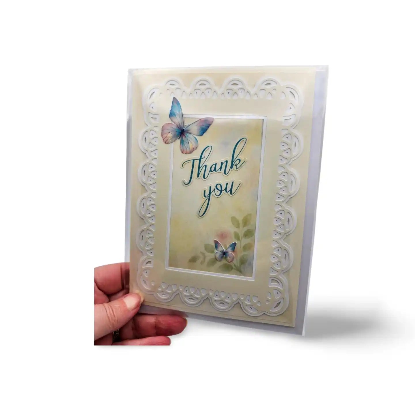 Card with butterflies and 'Thank you' text held by a hand on a white background