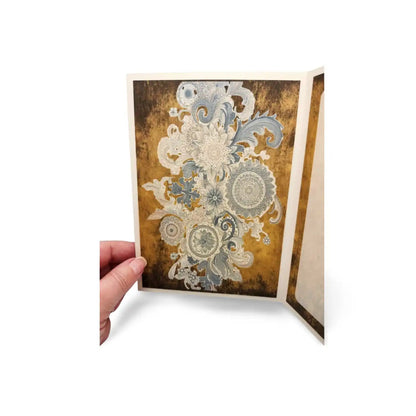 Decorative greeting card with floral design held by a hand on a white background