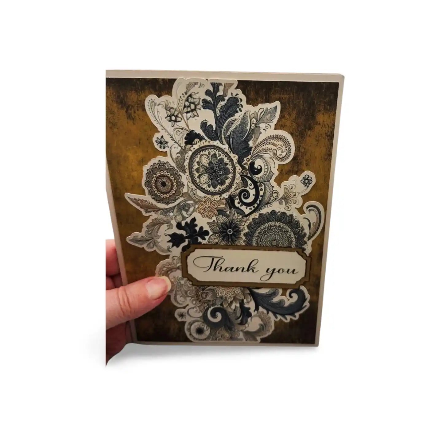 Decorative card with lace design and 'Thank you' text held by a hand on a white background