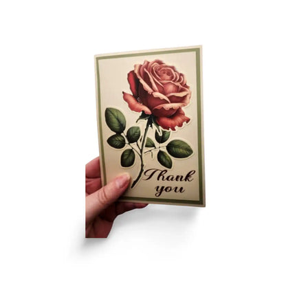 Card with a red rose and 'Thank you' text held by a hand on a white background