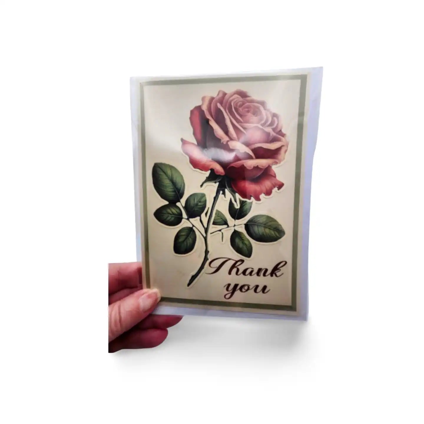 Greeting card with a rose design and 'Thank you' text held by a hand on a white background