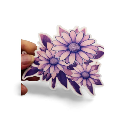 Hand holding a purple and pink floral sticker with a white background