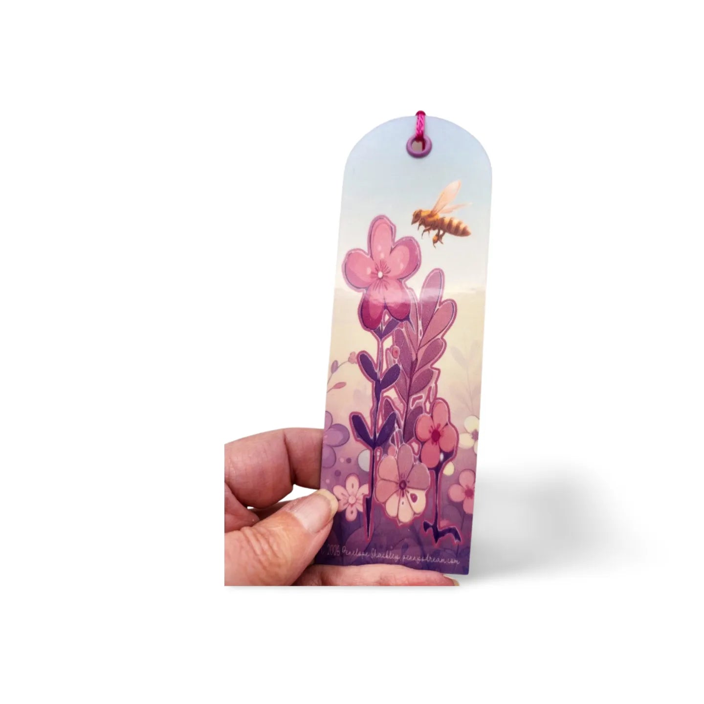 Hand holding a bookmark with floral design on a white background