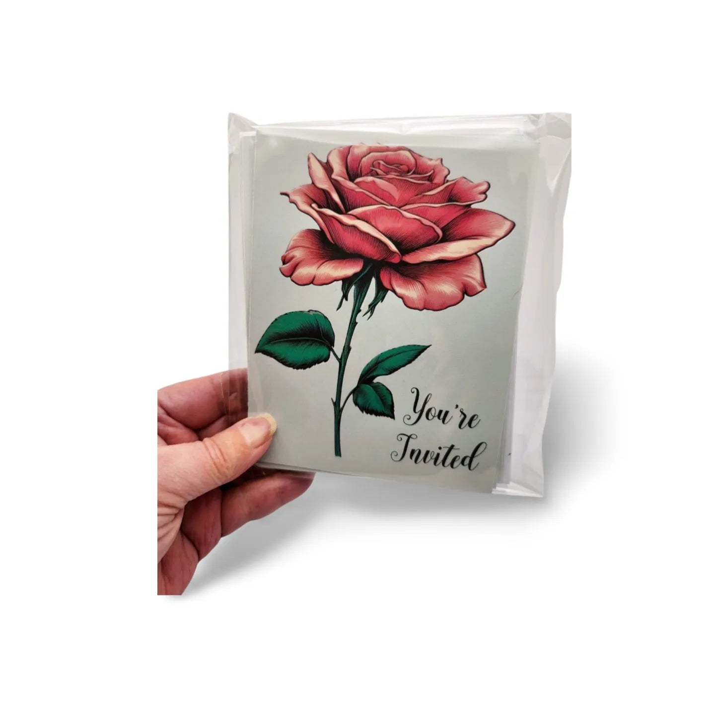 Hand holding a card with a red rose and 'You're Invited' text on a white background