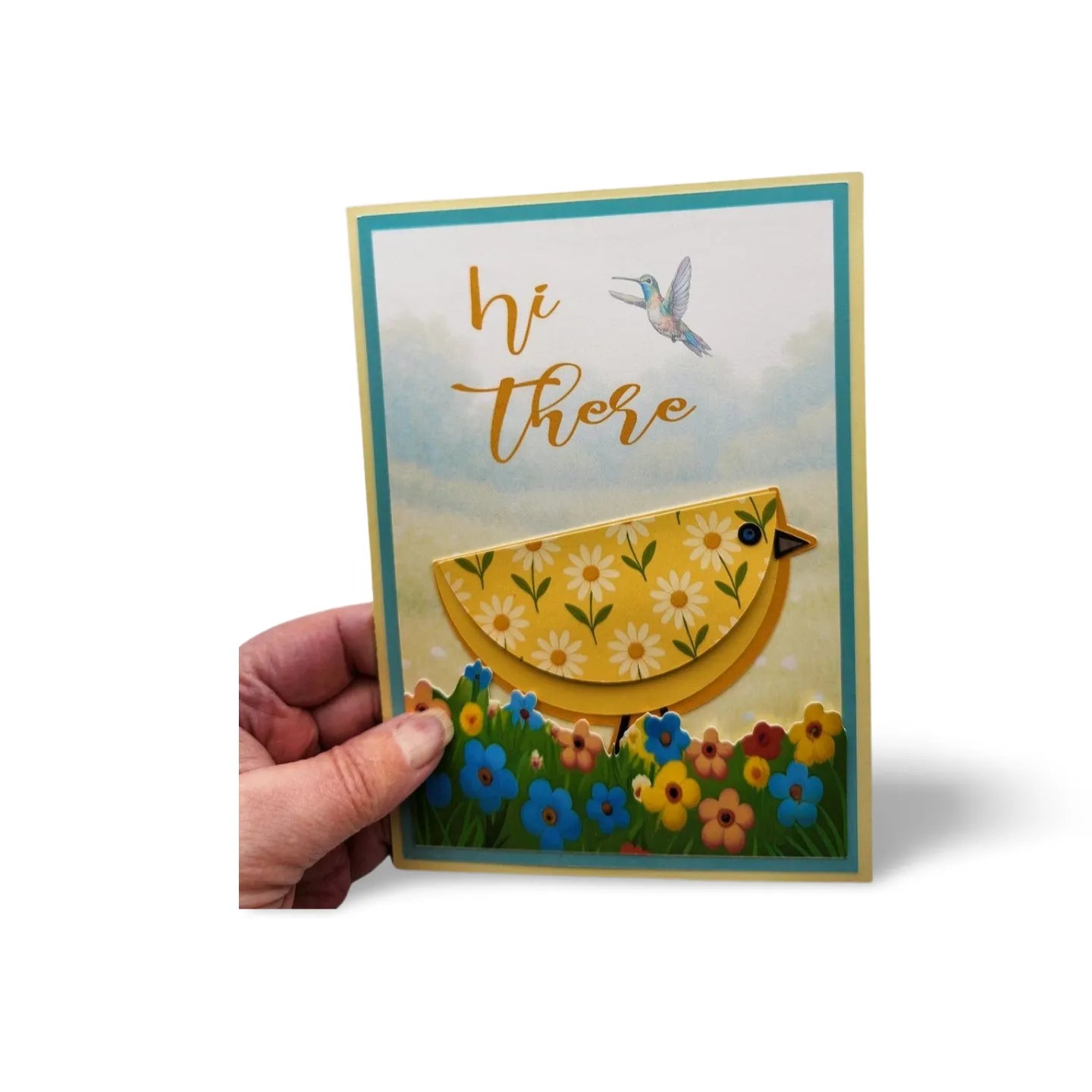 Hand holding a greeting card with a yellow bird design and 'hi there' text on a white background