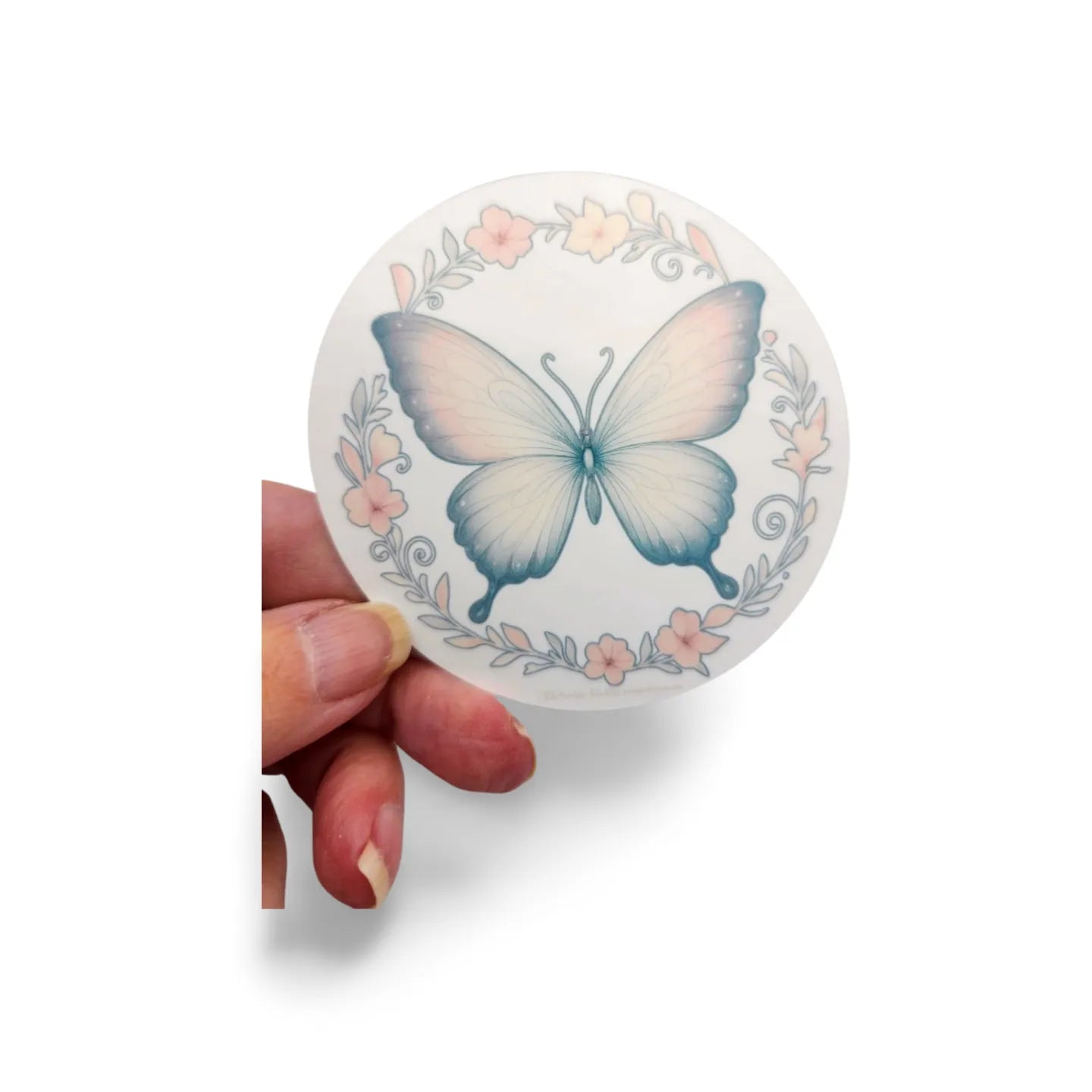 Round sticker with a butterfly design held by a hand on a white background