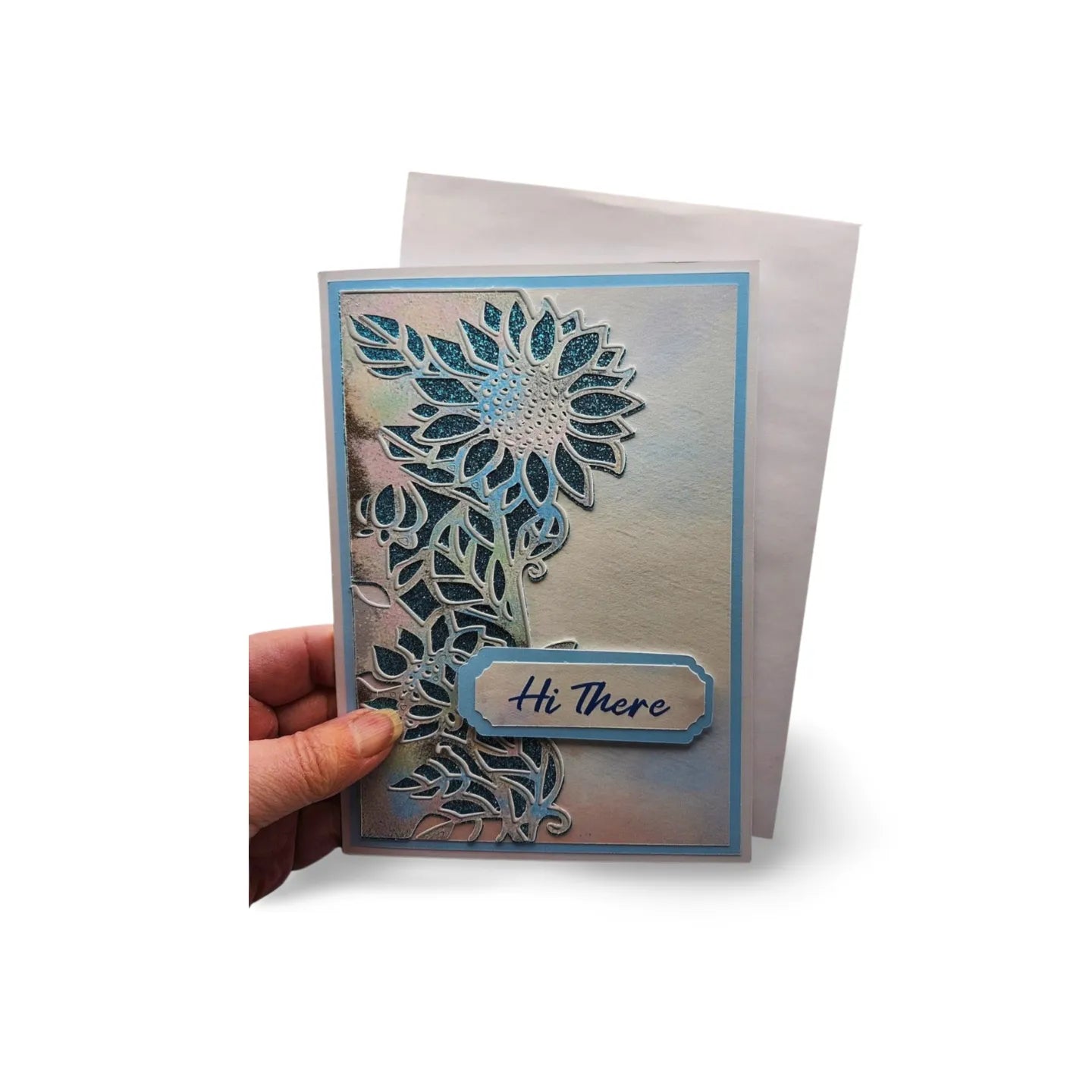 Greeting card with floral design and 'Hi There' text held by a hand on a white background