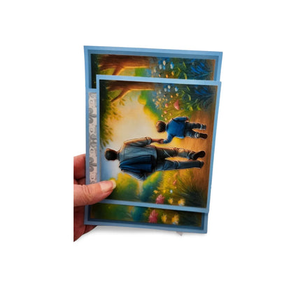Hand holding a colorful card with an illustration of a father and son in a garden.