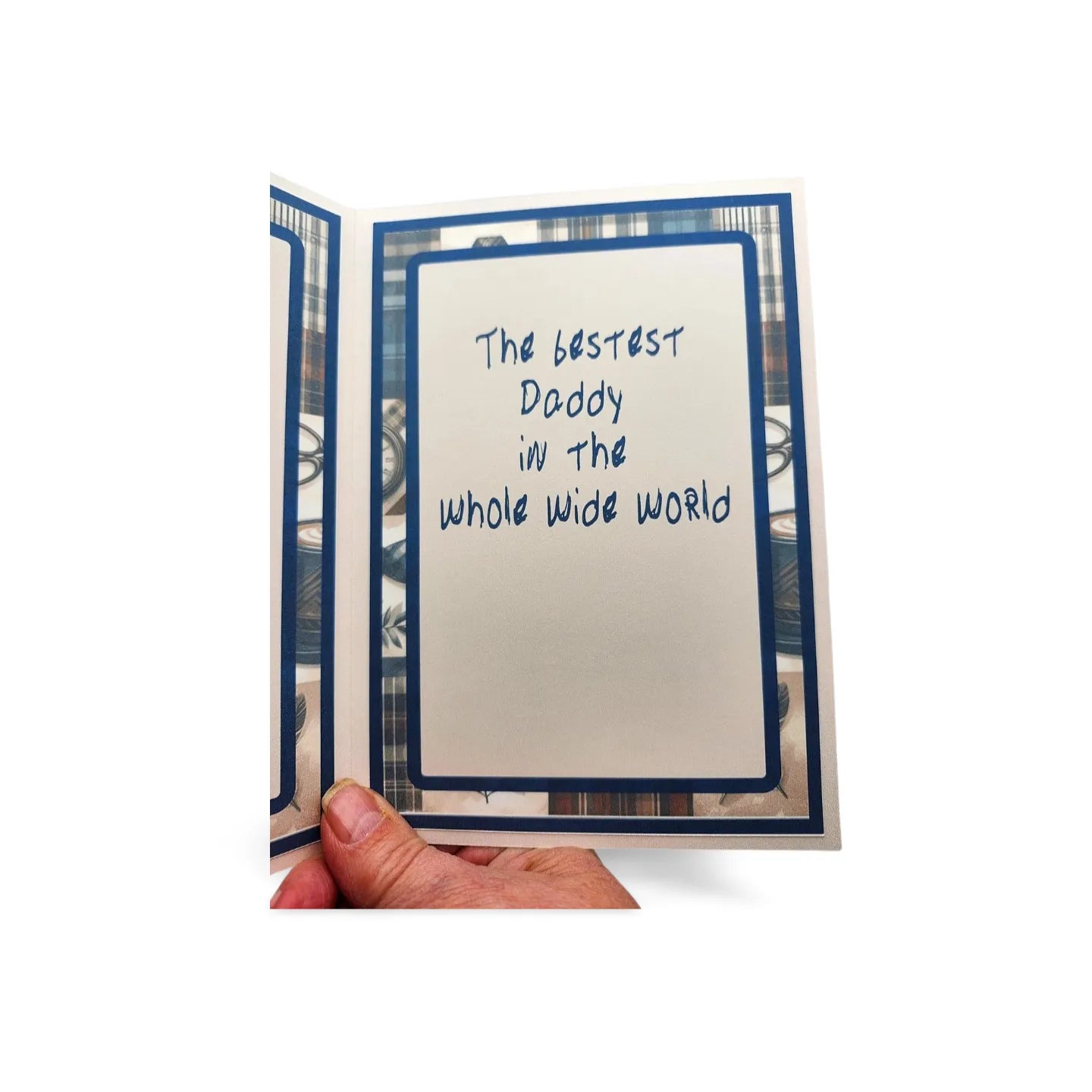 Hand holding a card with 'The bestest Daddy in the whole wide world' text on a white background