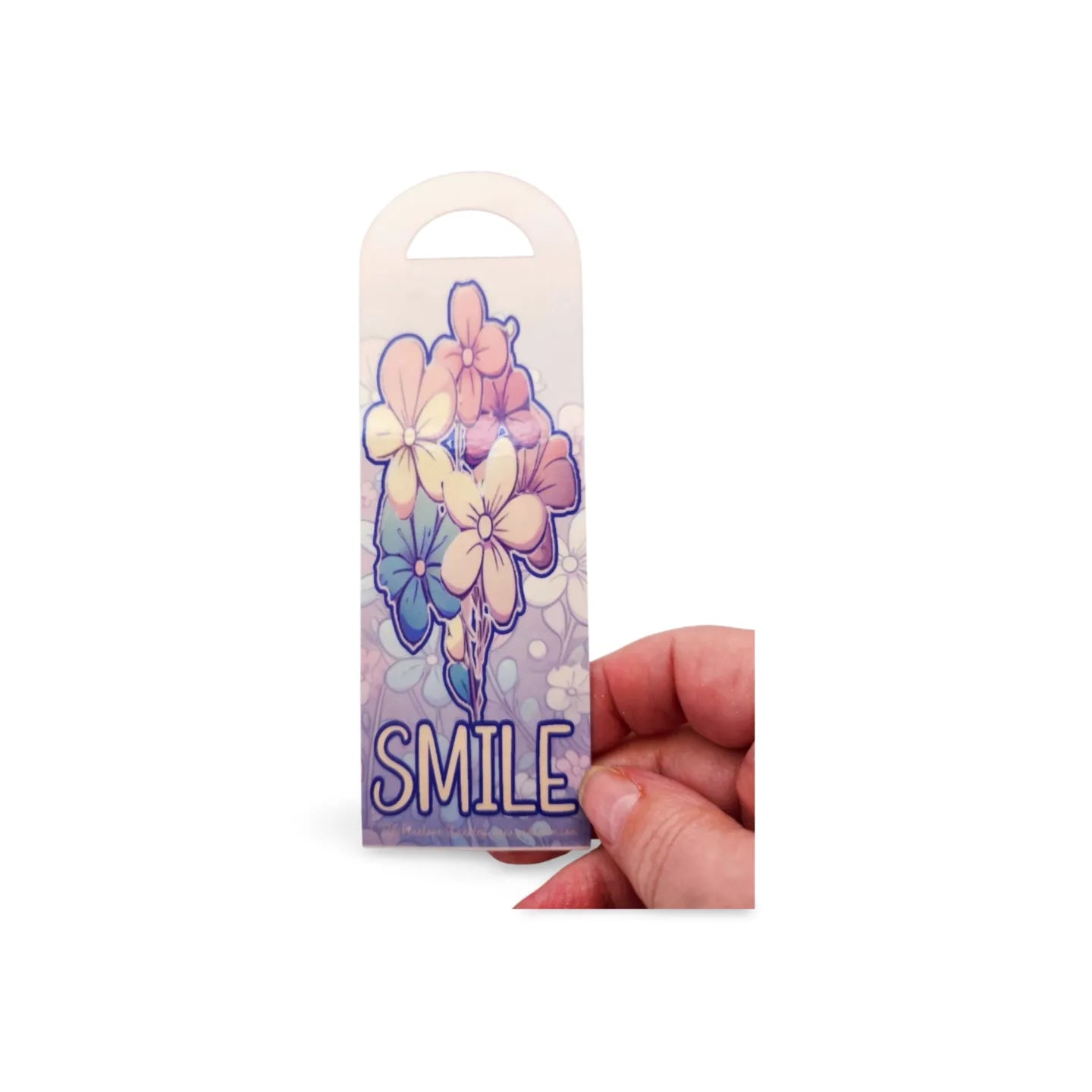 Floral design with 'SMILE' text held by a hand on a white background