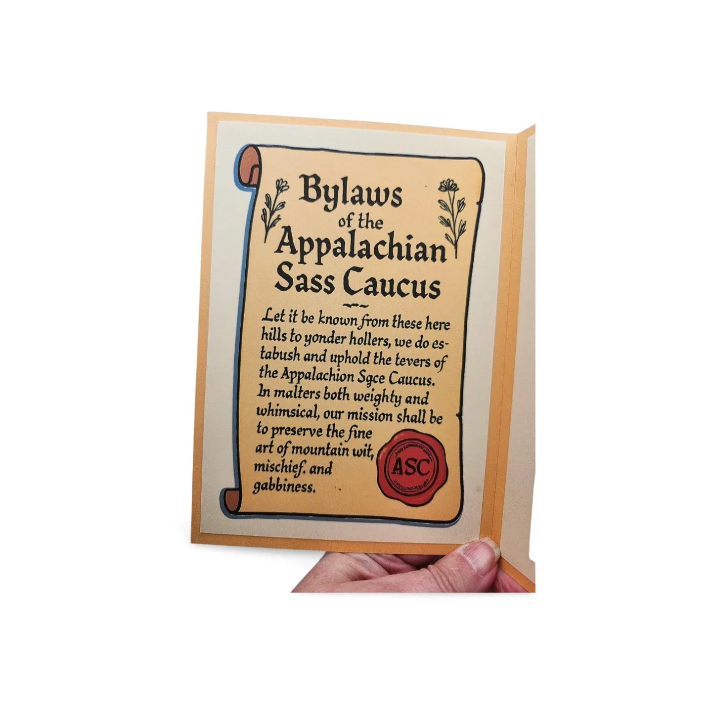 Card with 'Bylaws of the Appalachian Sass Caucus' text and a hand holding it.