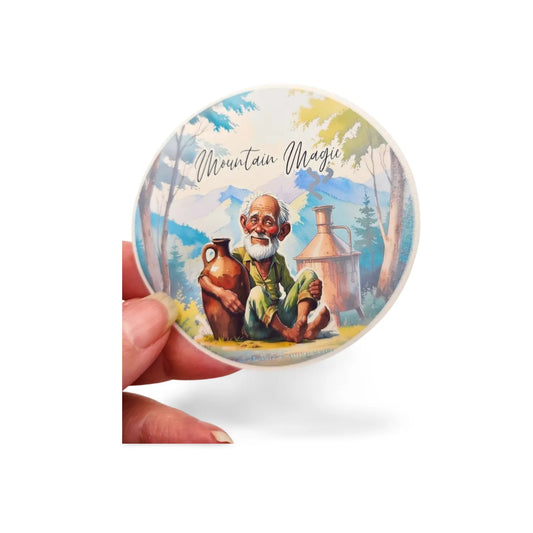 Round product with mountain-themed design and 'Mountain Magic' text, held by a hand on a white background.
