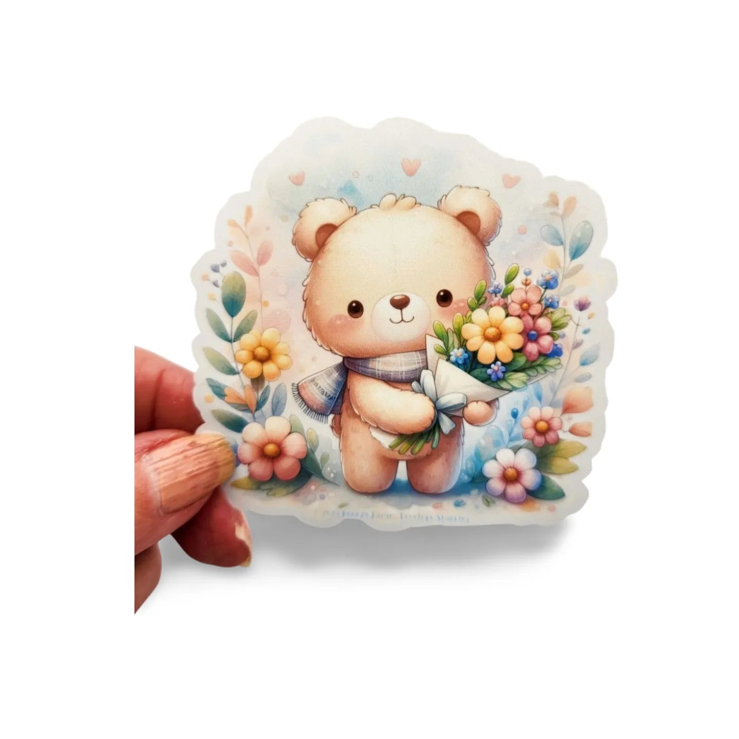 Sticker of a teddy bear holding flowers with a hand holding it on a white background