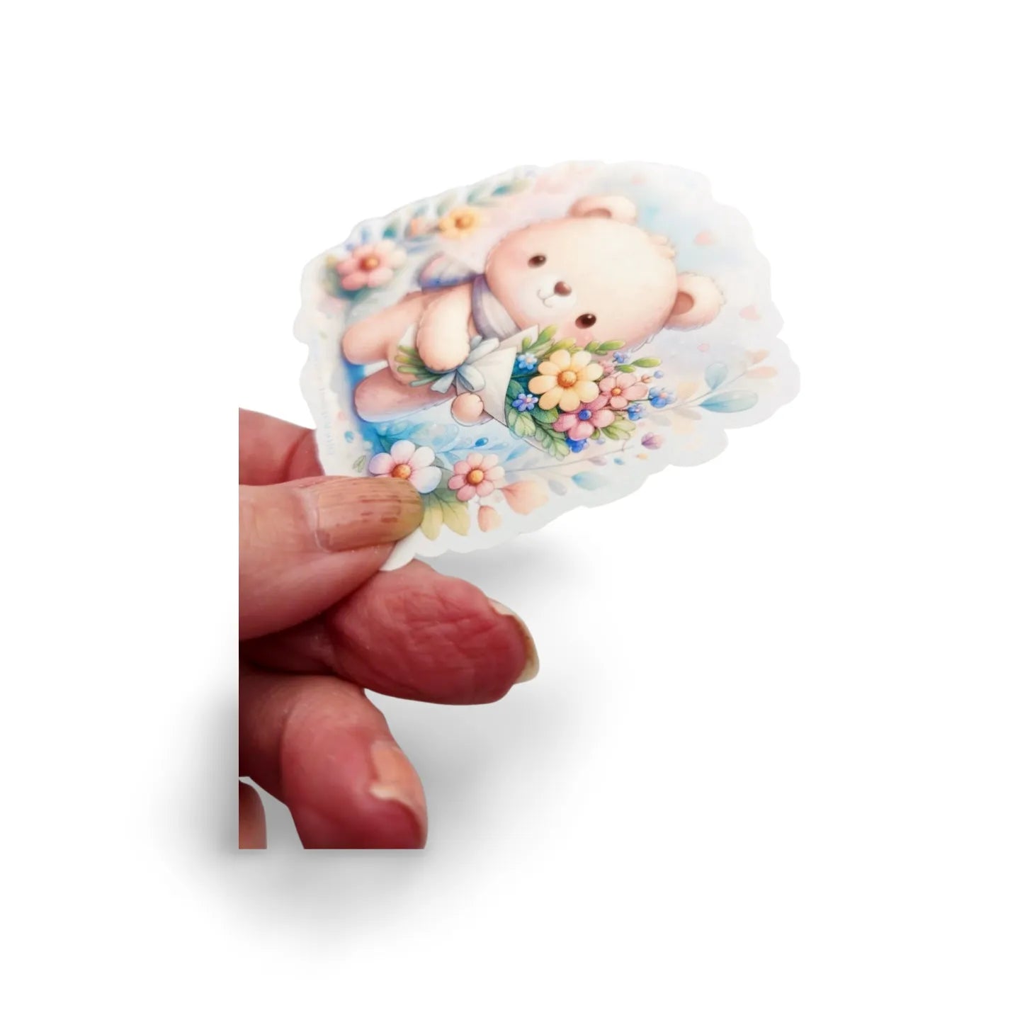 Sticker of a bear holding flowers held by a hand on a white background