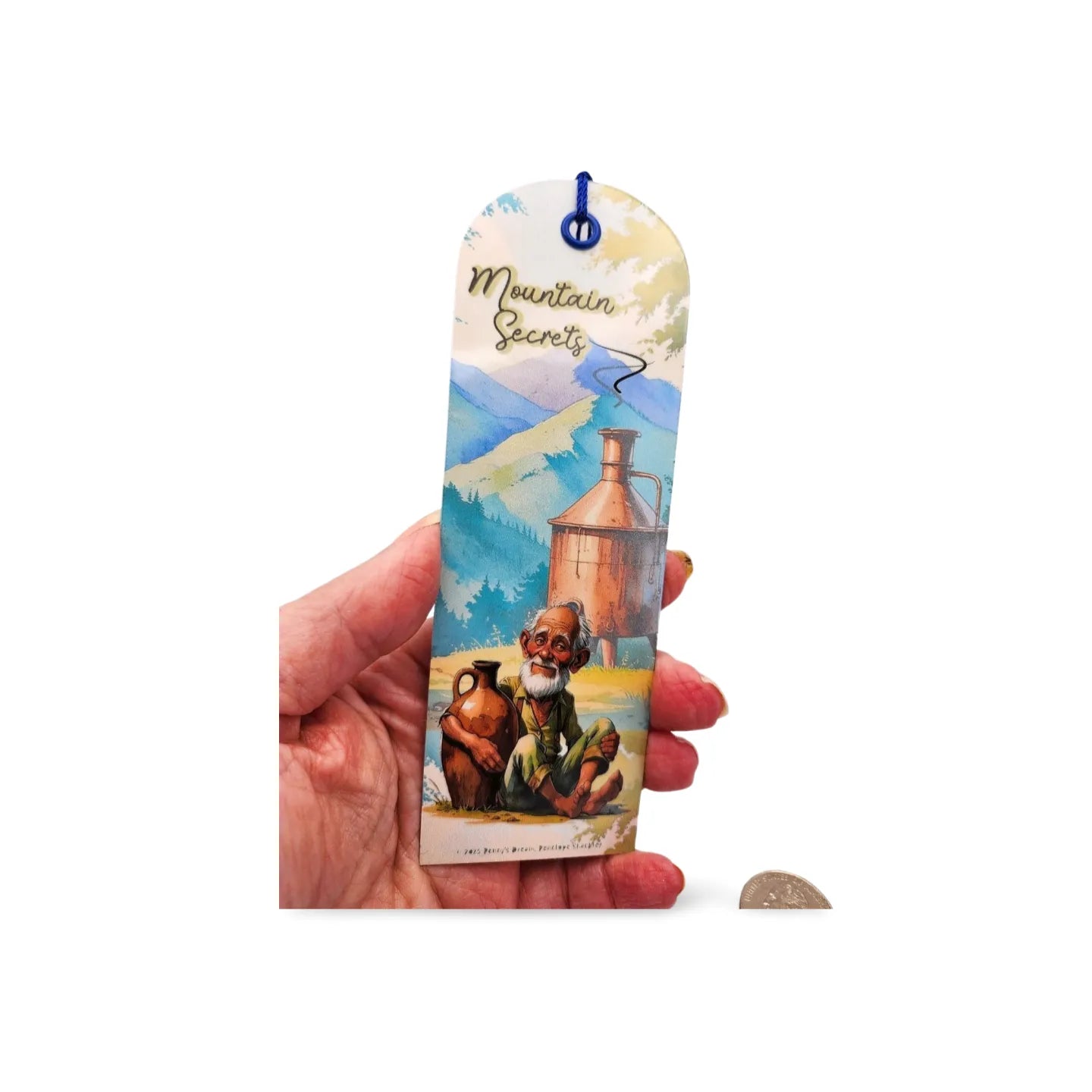 Hand holding a colorful bookmark with a mountain scene and character on a white background