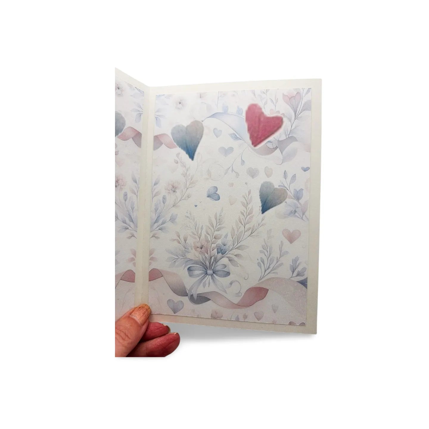 Hand holding a card with heart and floral designs on a white background