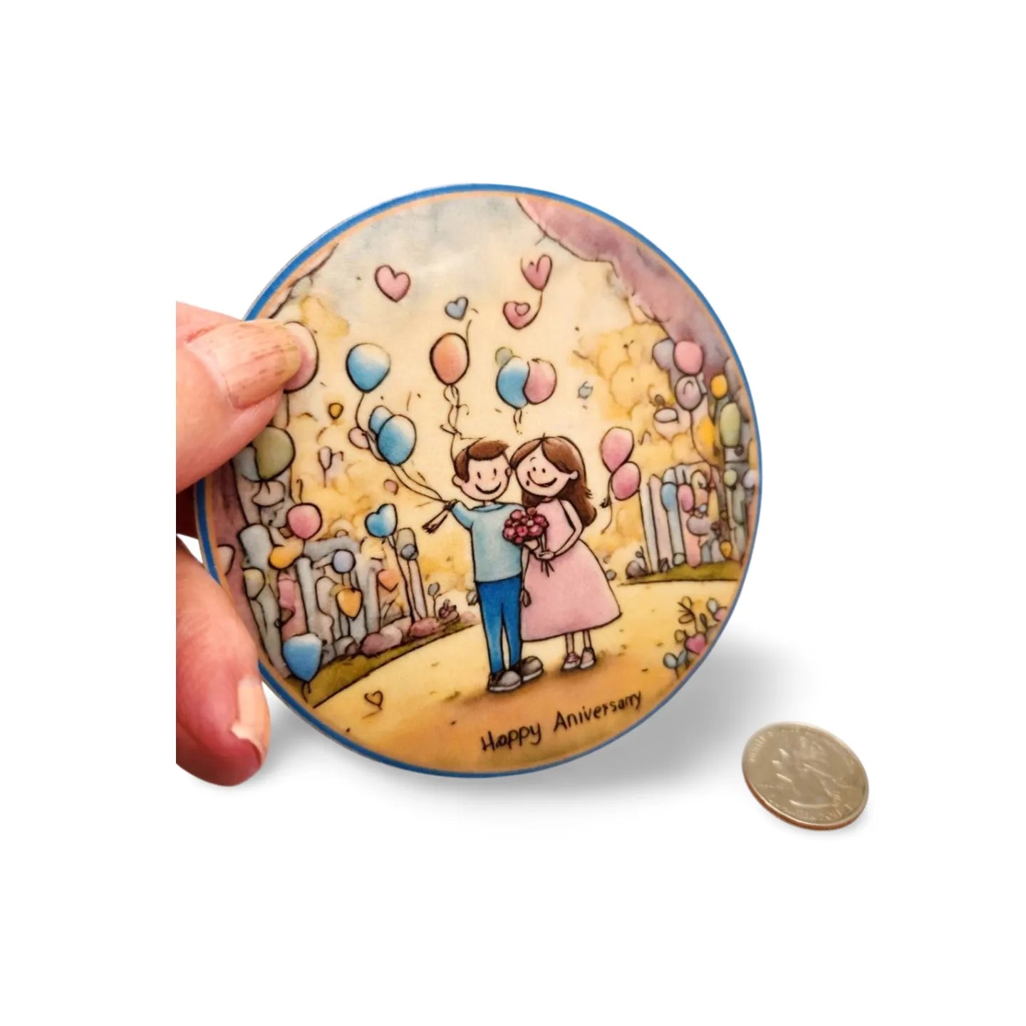 Round decorative item with a couple and balloons illustration, held by a hand.