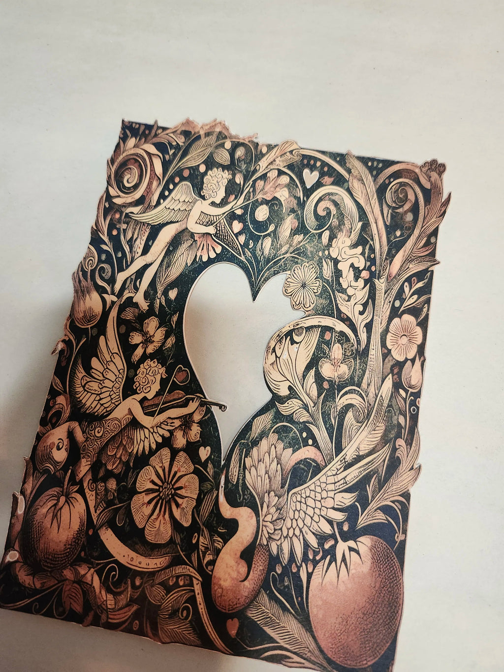 Decorative paper cutout with intricate designs of birds, flowers, and fairies on a white background