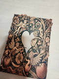 Decorative paper cutout with intricate designs of birds, flowers, and fairies on a white background