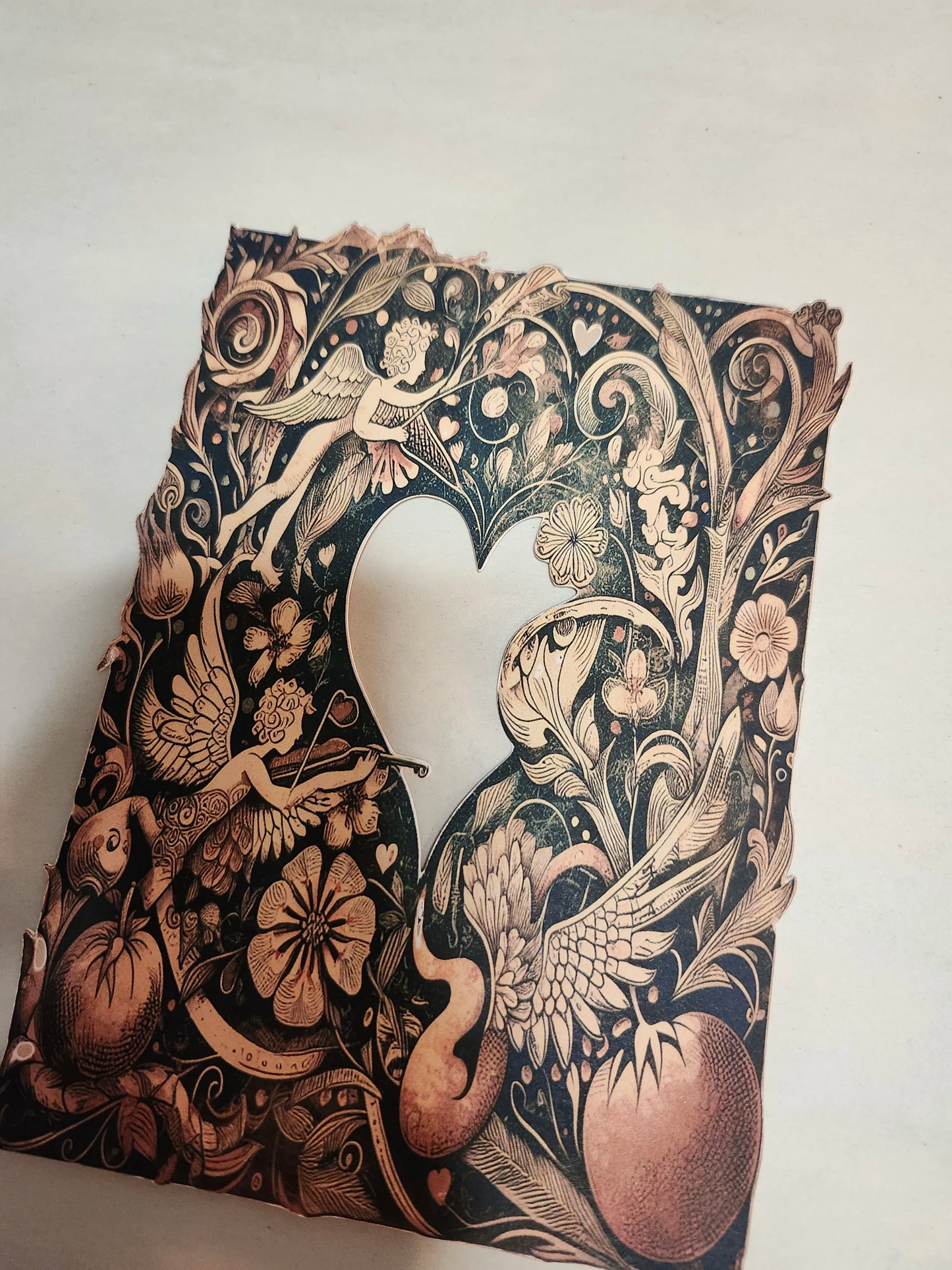 Decorative paper cutout with intricate designs of birds, flowers, and fairies on a white background