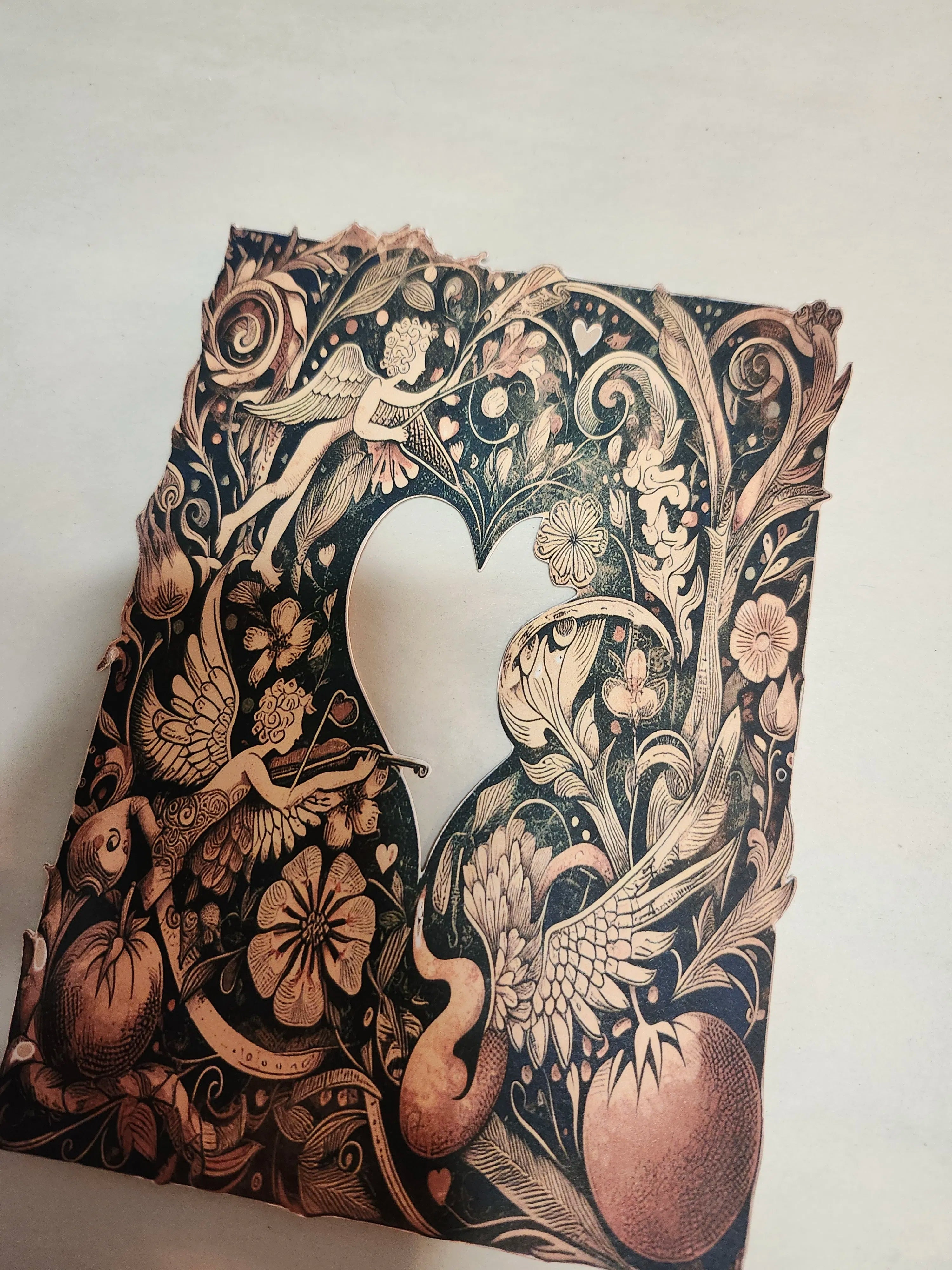 Decorative paper cutout with intricate designs of birds, flowers, and fairies on a white background