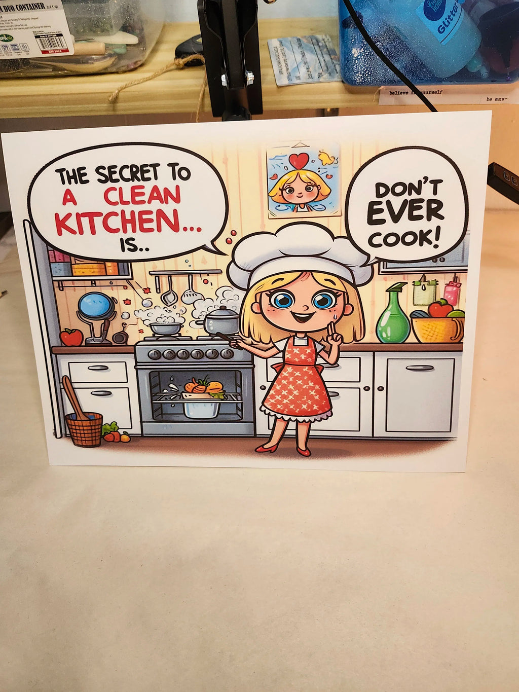 Cartoon card with a character in a kitchen and humorous text about cleaning a kitchen.