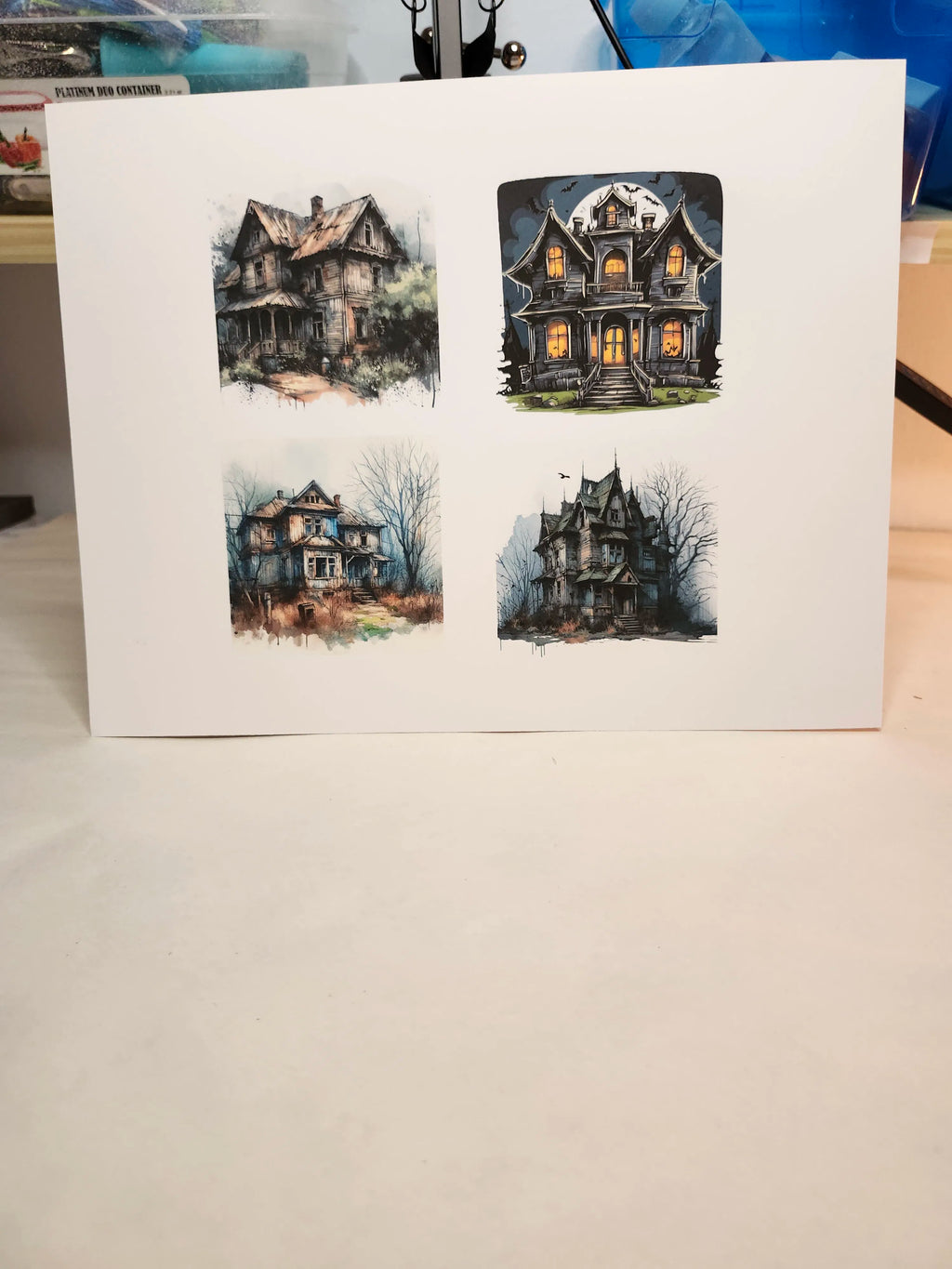 Four illustrations of haunted houses on a white card.