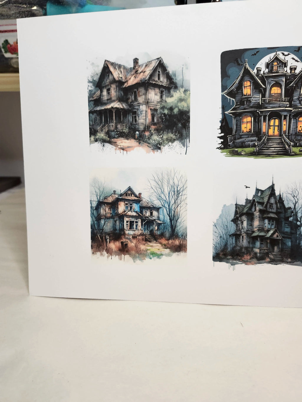 Set of greeting cards with illustrations of haunted houses on a white surface.
