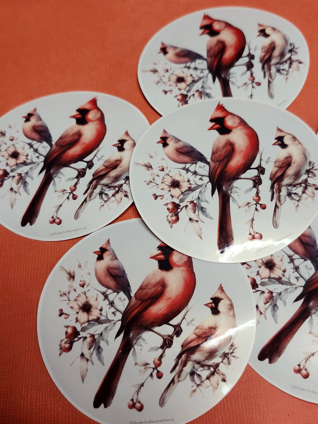 Circular stickers with cardinals and floral designs on a brown background