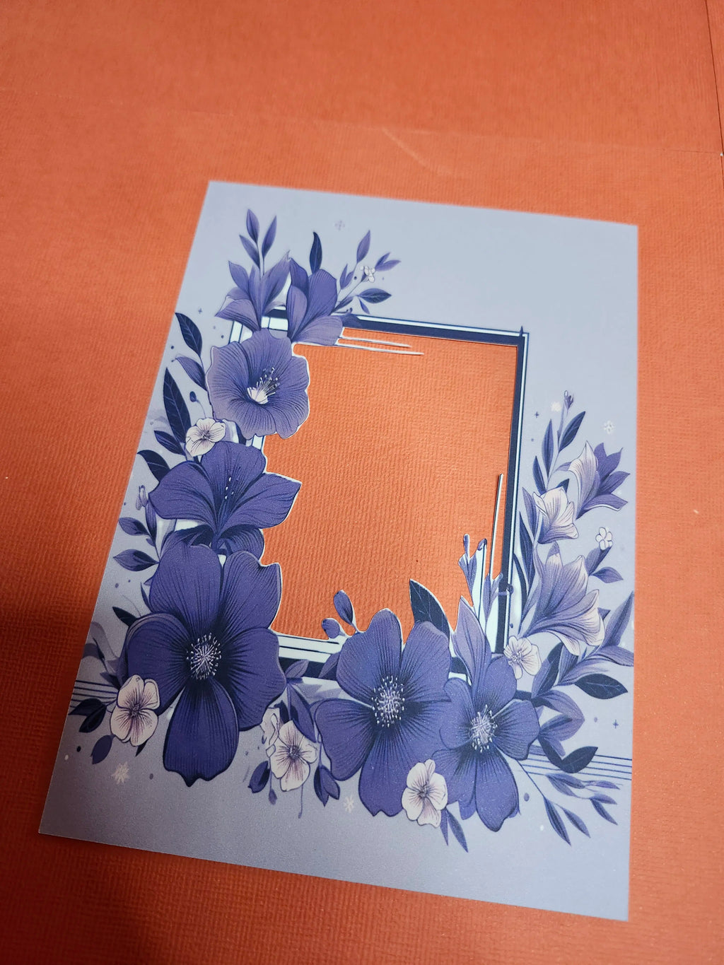 Floral design on a light blue card with a brown envelope on an orange background