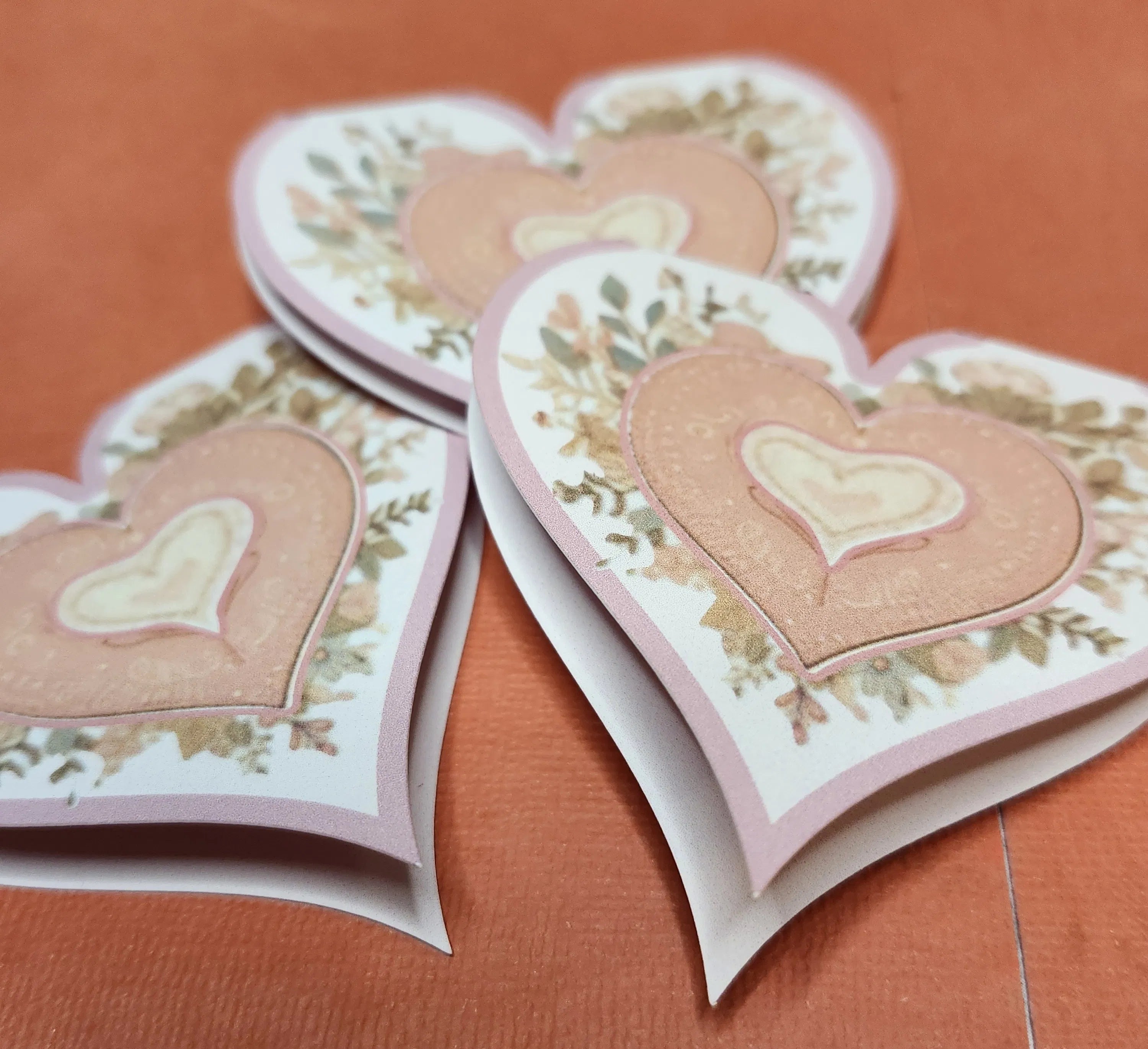 Heart-shaped cards with floral designs on an orange background