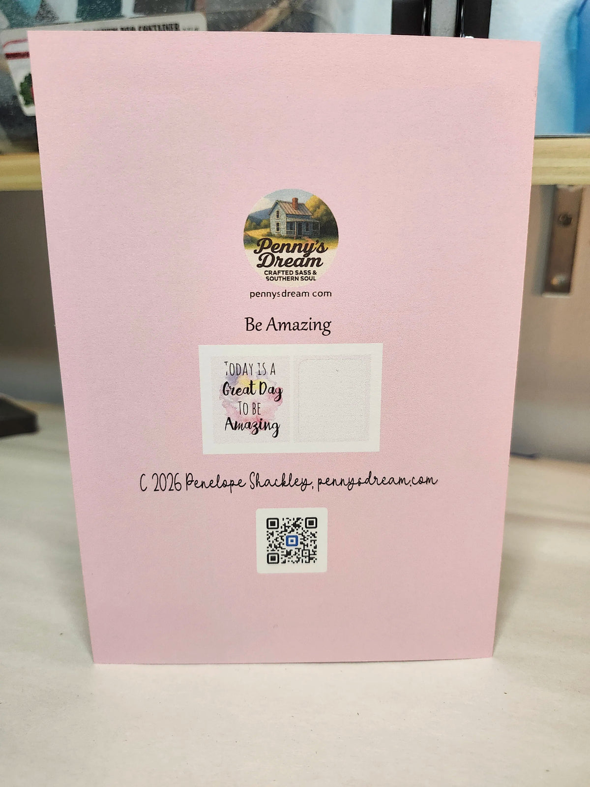 Pink card with text and a logo on a white surface