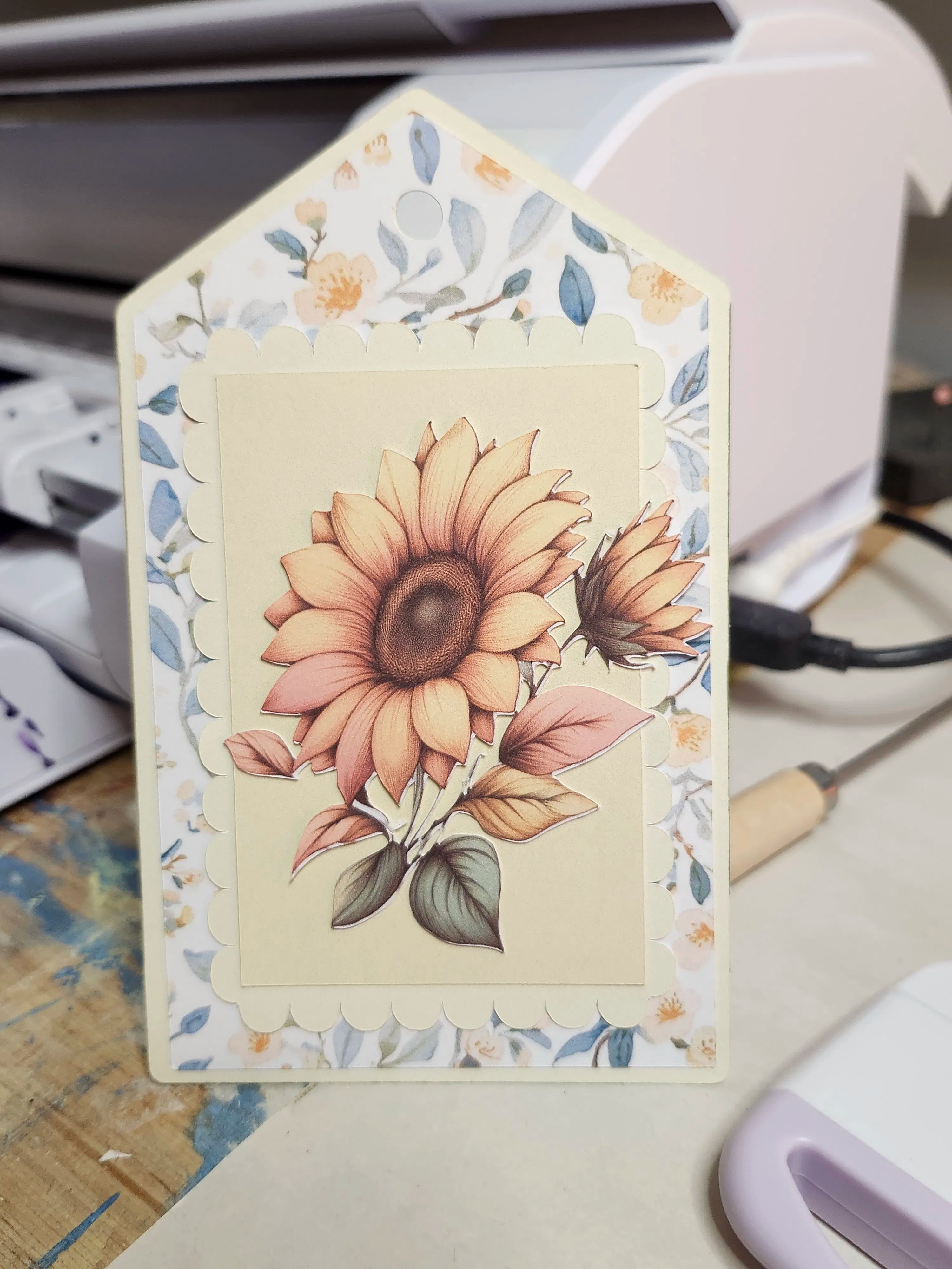 Decorative card with sunflower design on a desk with office equipment in the background