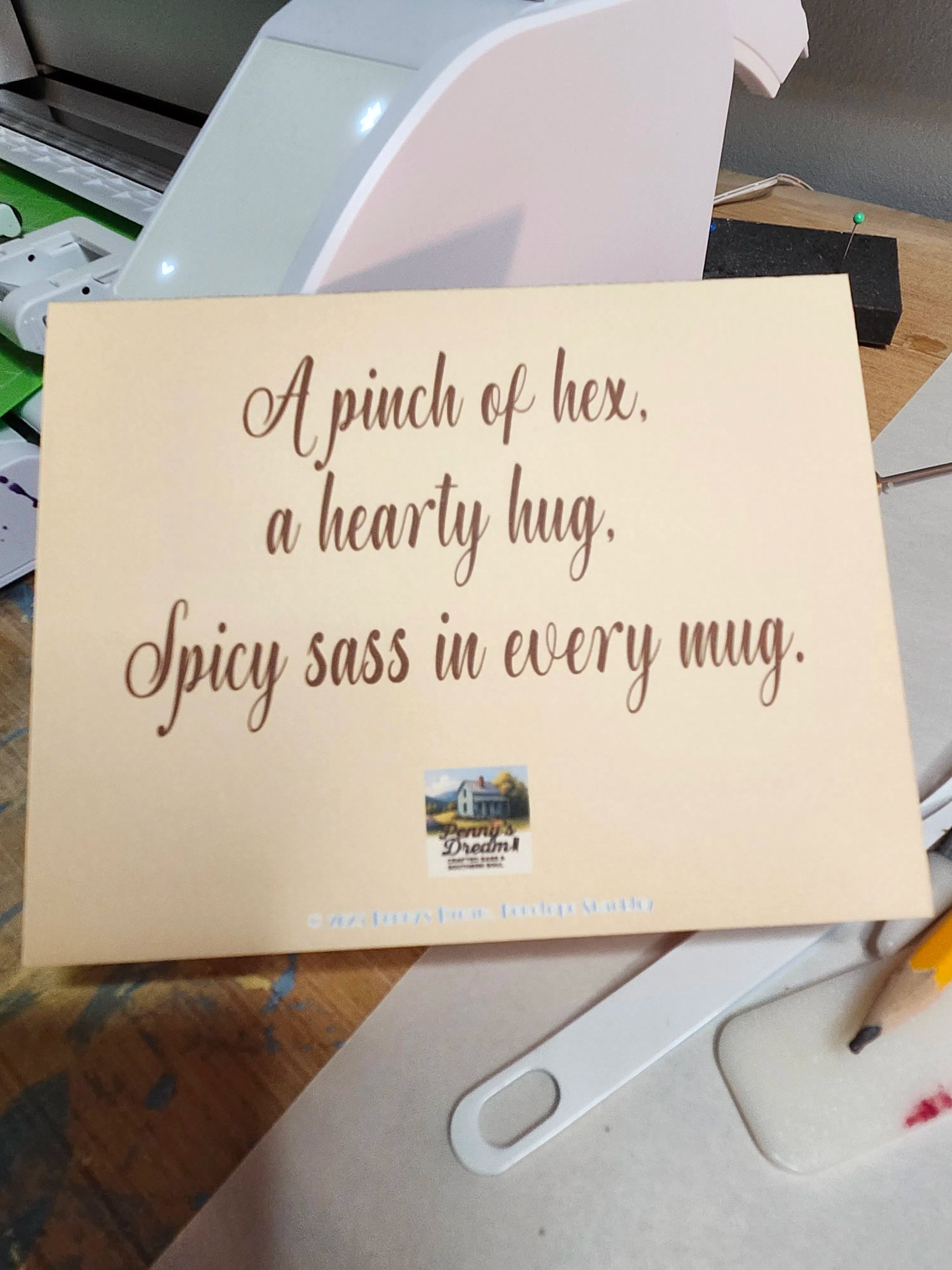 Wooden sign with text 'A pinch of hex, a hearty hug, Spicy sass in every mug.' on a desk.
