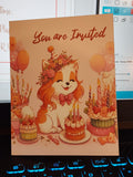 Invitation card with a dog illustration, balloons, and cake on a desk.