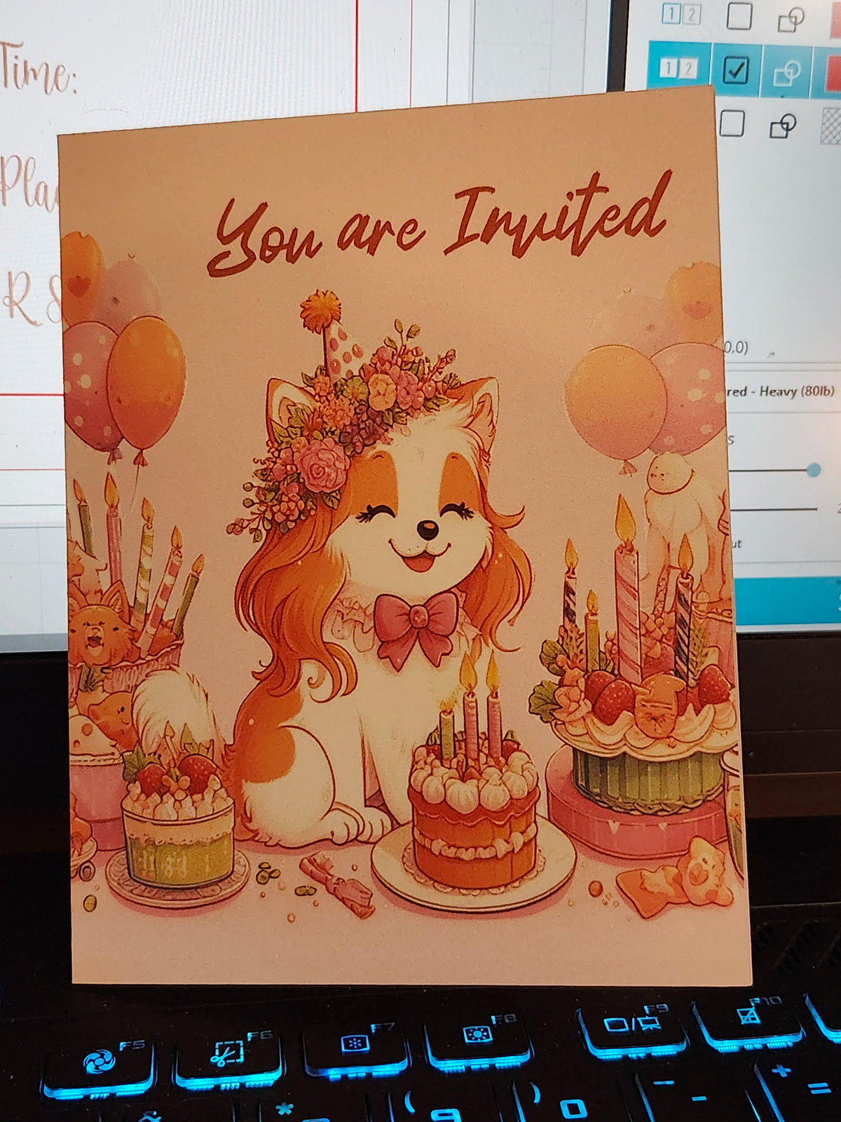 Invitation card with a dog illustration, balloons, and cake on a desk.
