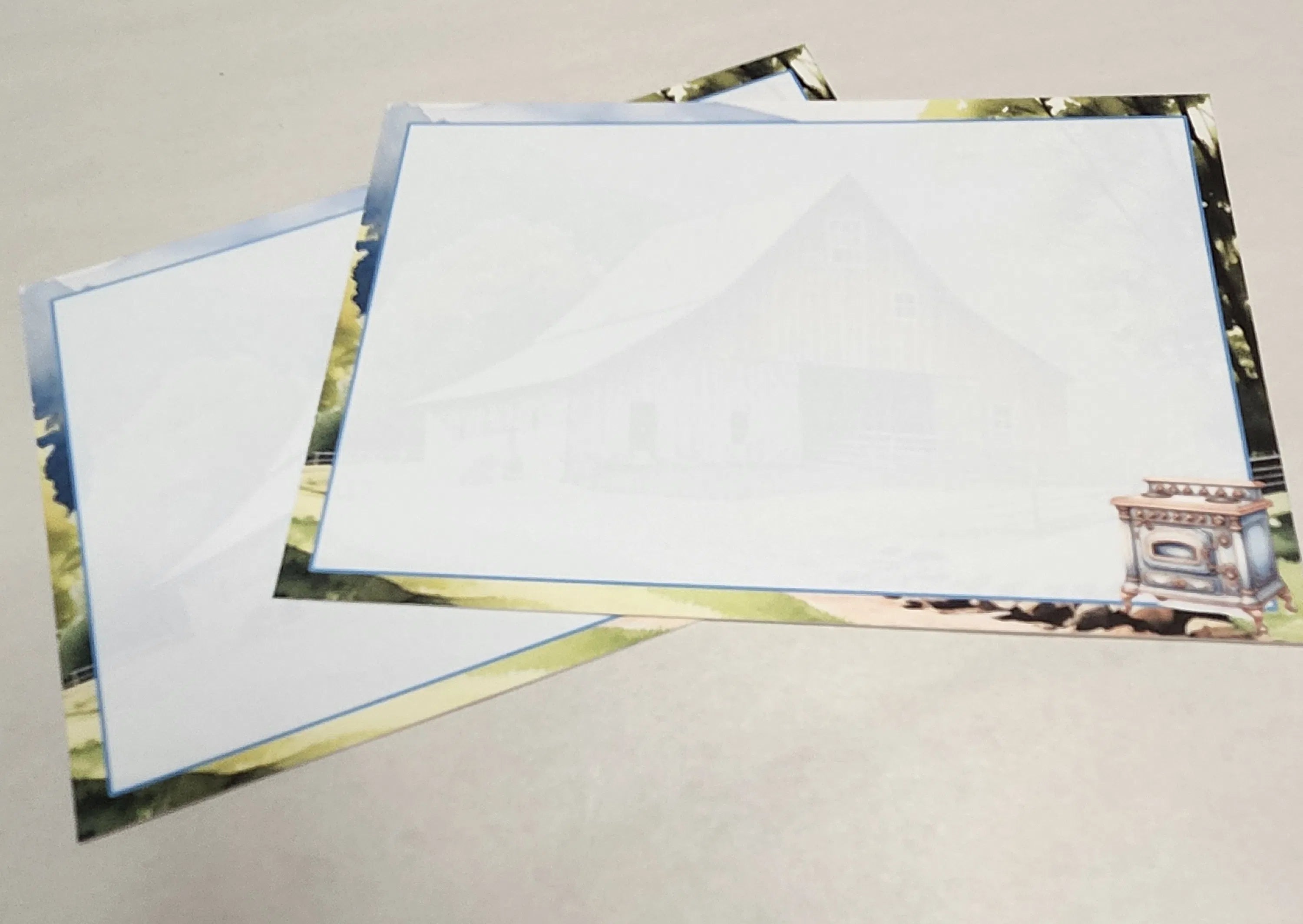 Two blank greeting cards with scenic designs on a gray surface
